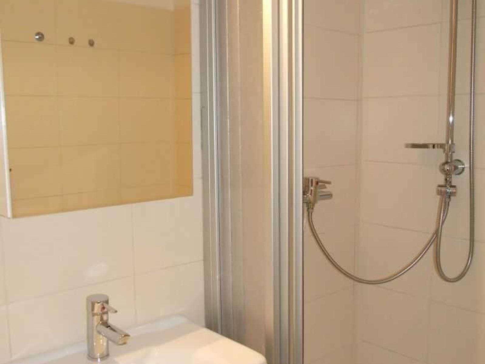 Bad mit Dusche, Waschbecken und Spiegel