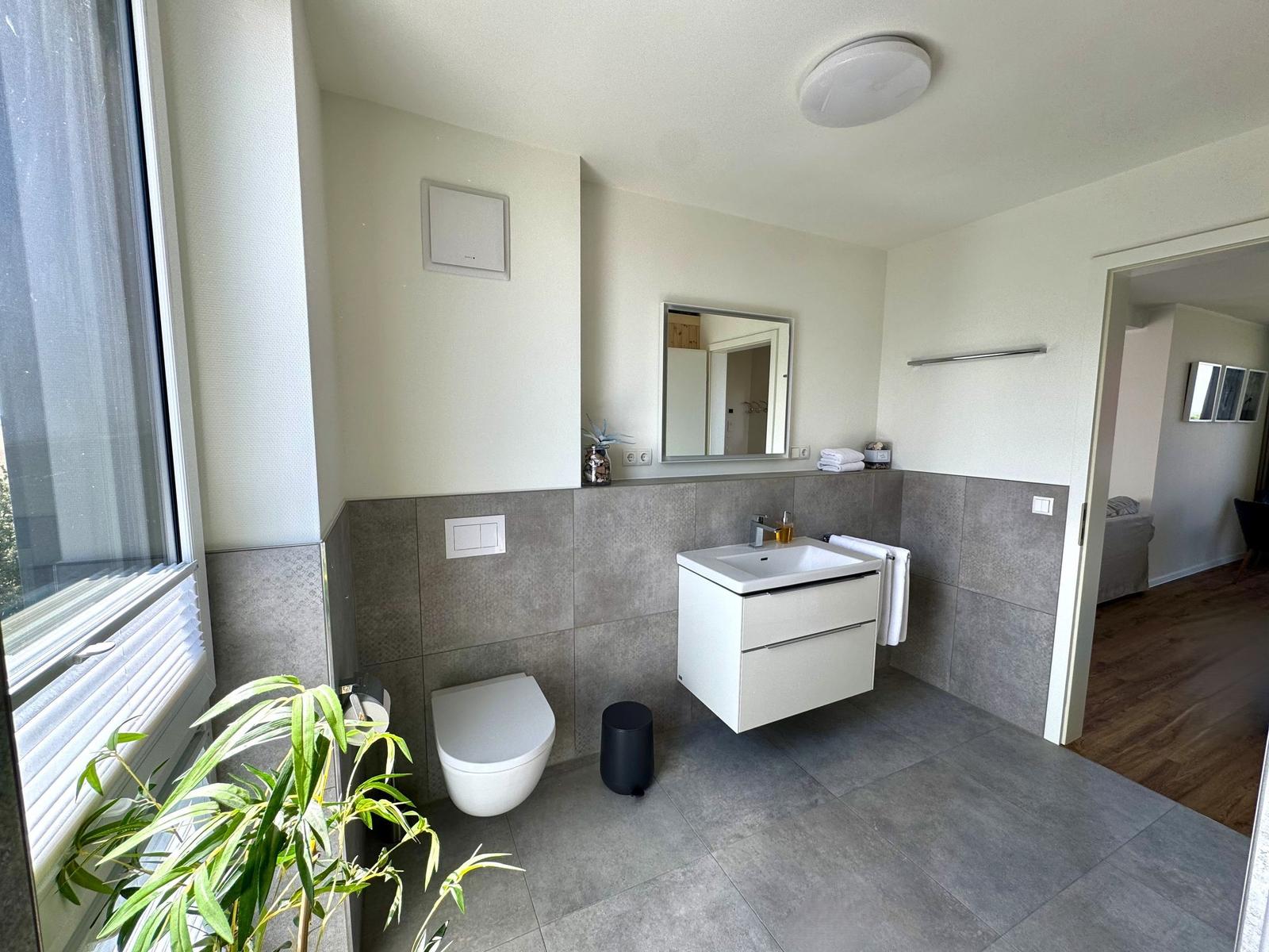 Badezimmer mit Waschbecken, Toilette und Fenster