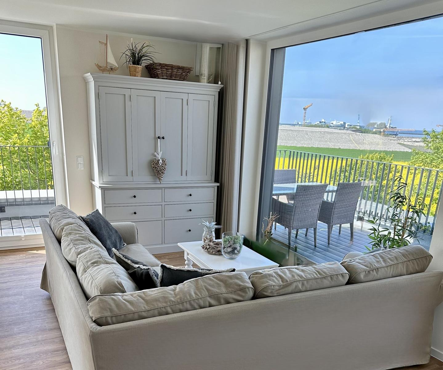 Wohnzimmer mit Sofa, Schrank und Balkonblick auf Hafen
