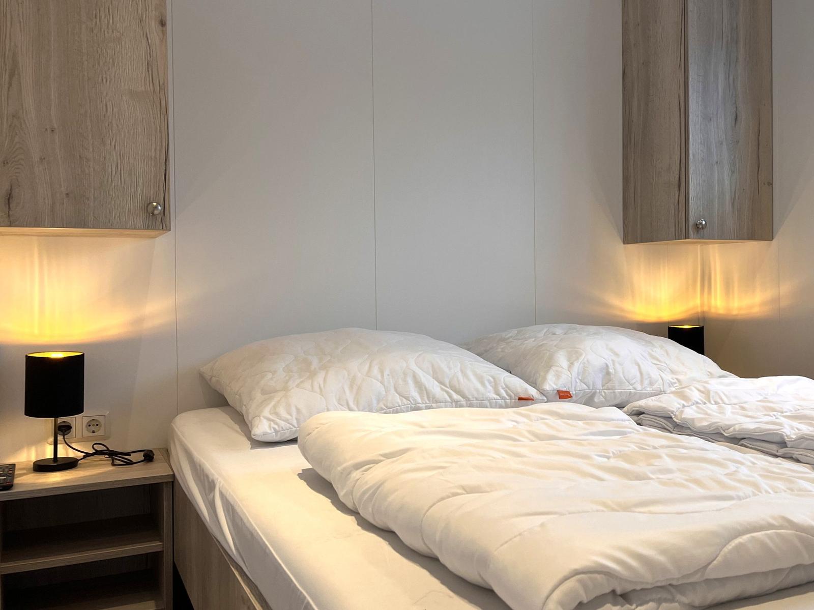 Schlafzimmer mit Bett, Nachttisch und Wandregalen.