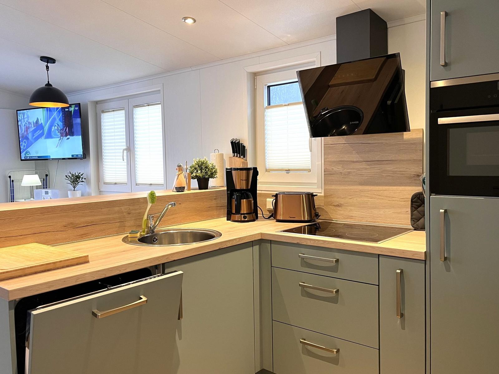 Küche mit Holzoberfläche, Spüle, Herd und integriertem Kühlschrank.