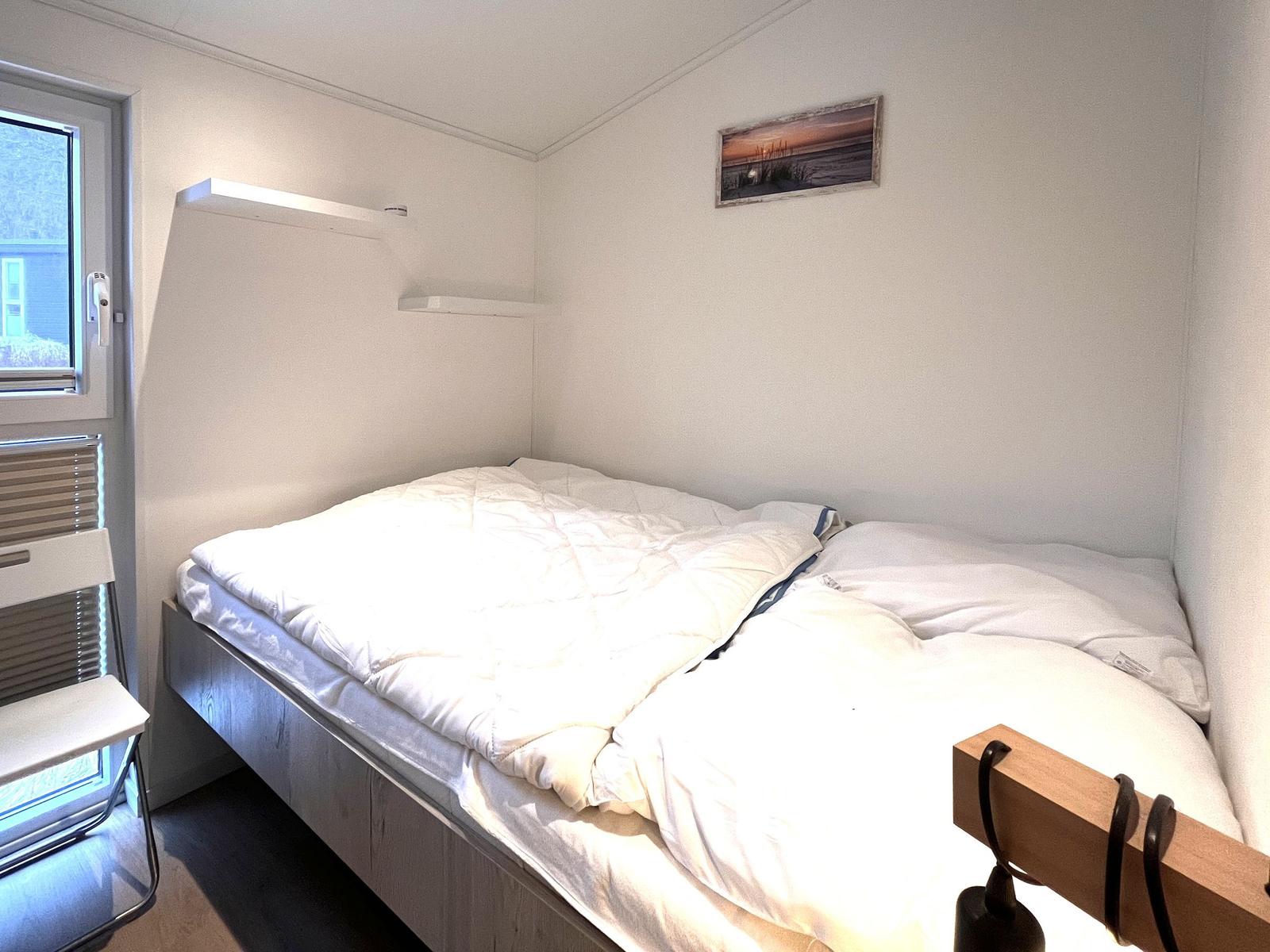 Schlafzimmer mit Bett, Fenster und Wandbild.