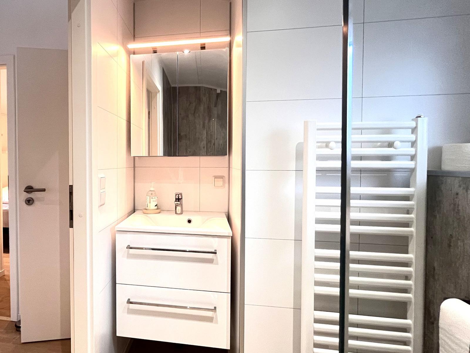 Badezimmer mit Waschbecken, Spiegel und Heizkörper