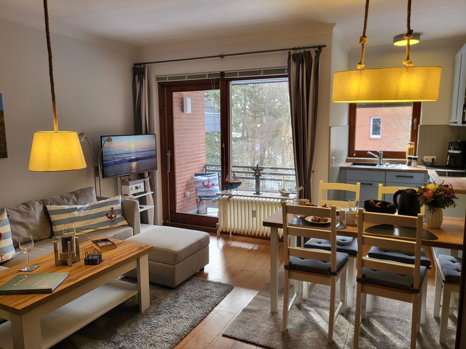 Wohn- und Essbereich mit Küchenzeile, Balkon und Fernseher.