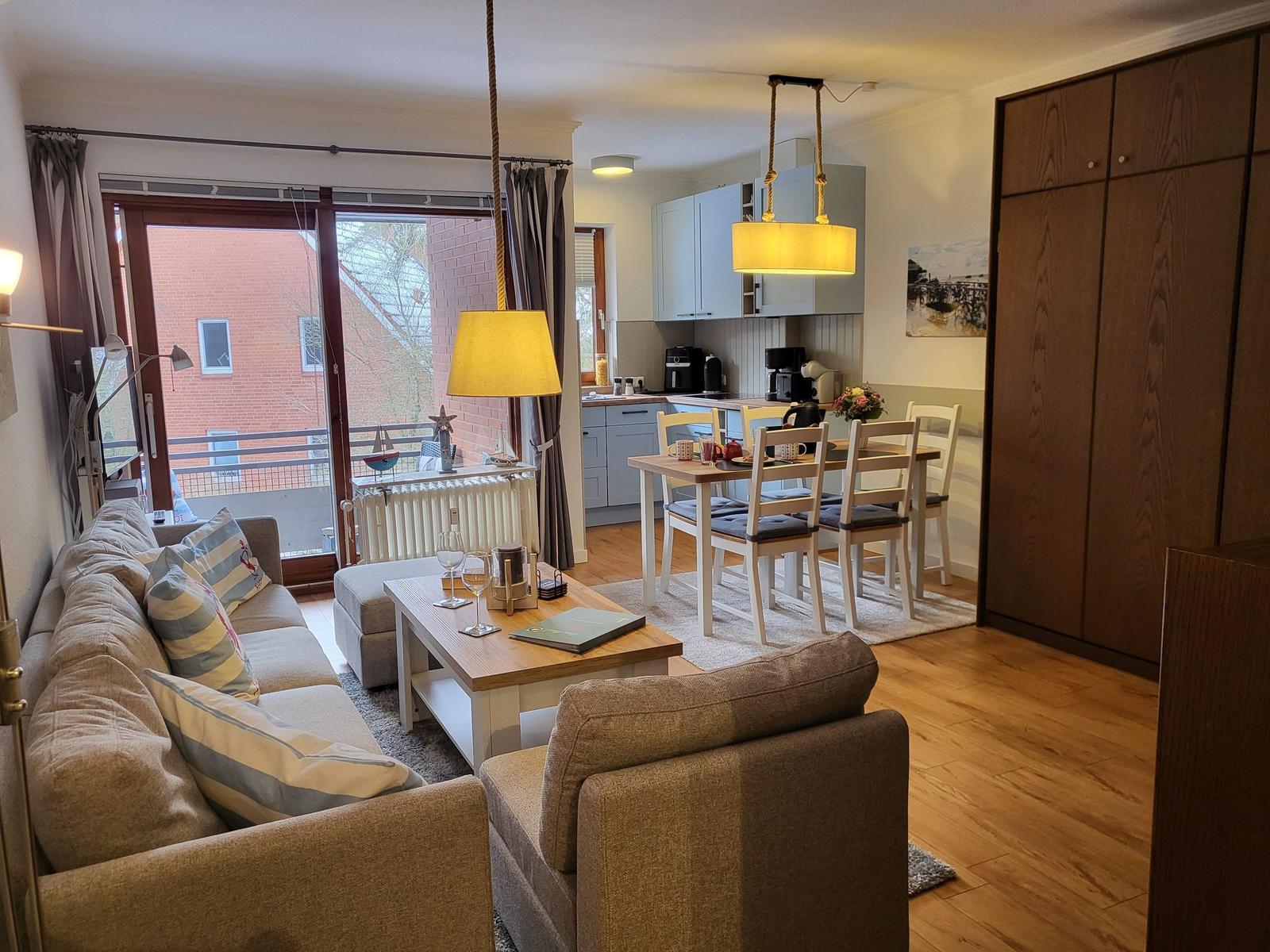 Wohn- und Essbereich mit Sofa, Tisch und Küchenzeile.