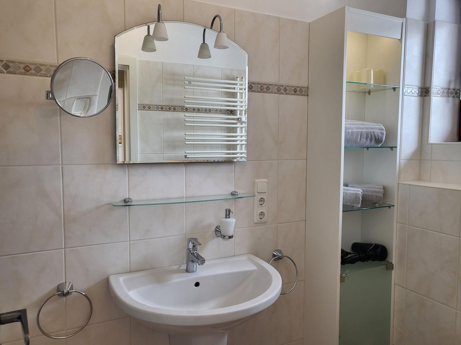 Badezimmer mit Waschbecken, Spiegel und Aufbewahrung