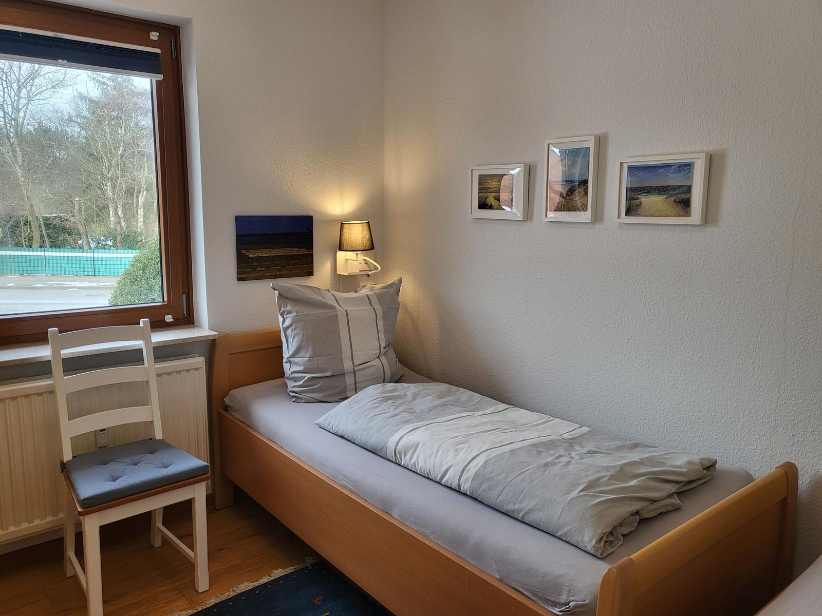 Ein Schlafzimmer mit einem Bett, einem Stuhl und einem Fenster.