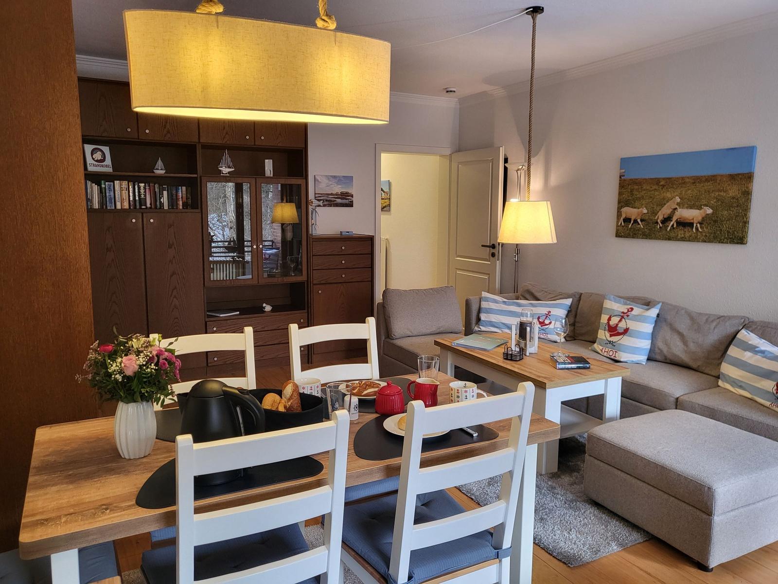 Essbereich mit Tisch und Stühlen. Wohnbereich mit Sofa und Couchtisch.