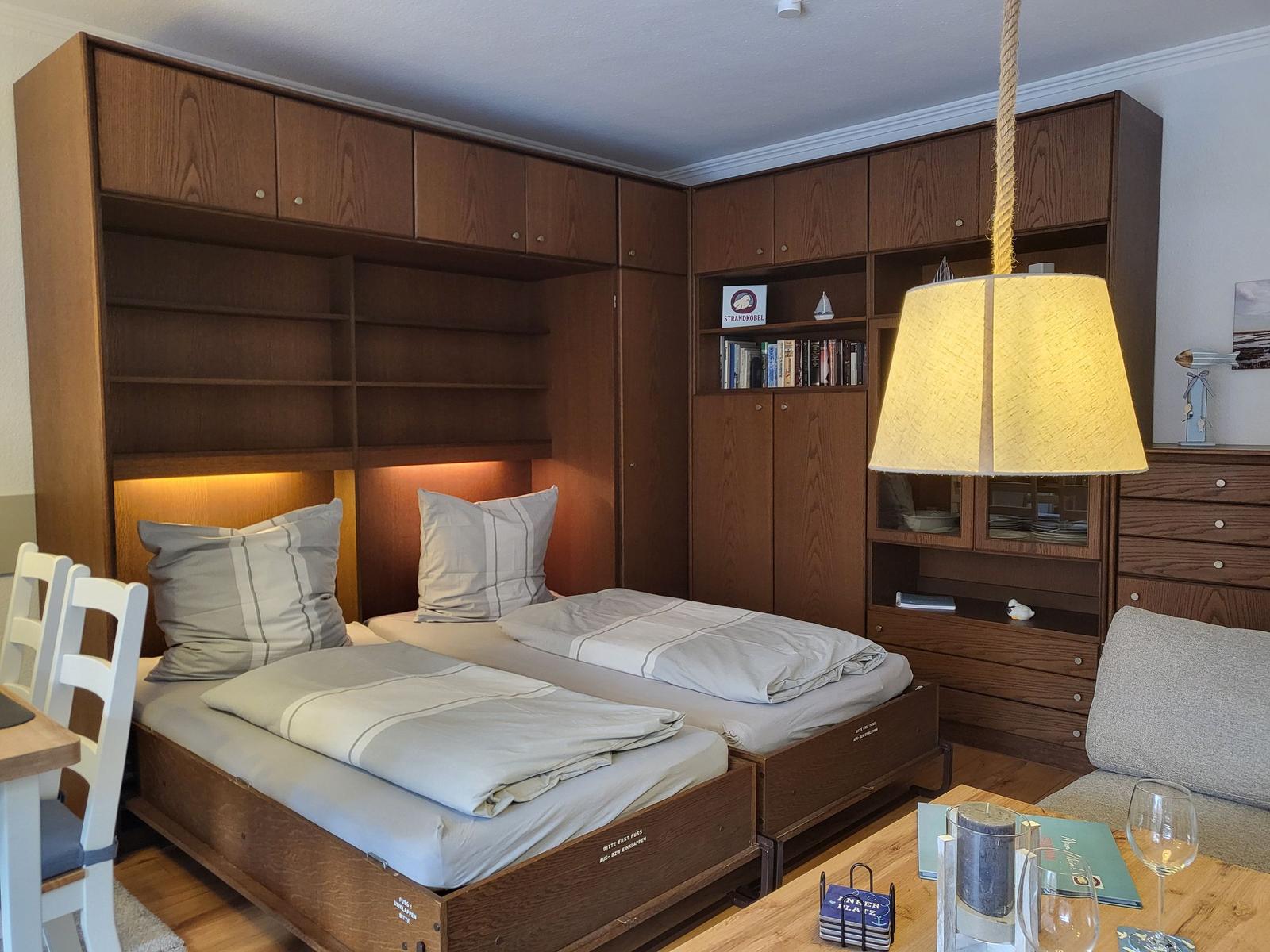 Zimmer mit zwei Betten, Holzmöbel und einer Lampe.