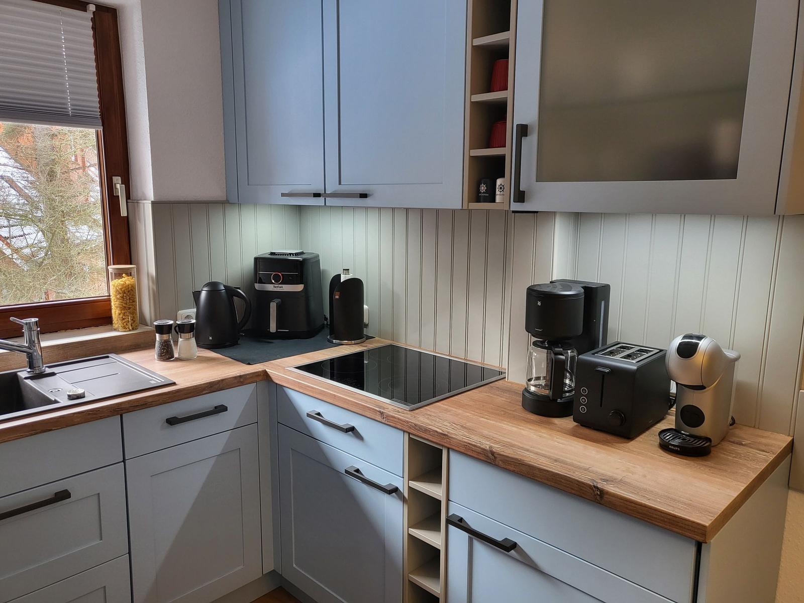 Küche mit Holz Arbeitsplatte, blauen Schränken und modernen Geräten.