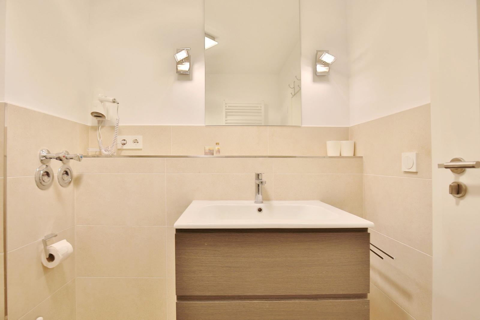 Bad mit Waschbecken, Spiegel und Dusche.