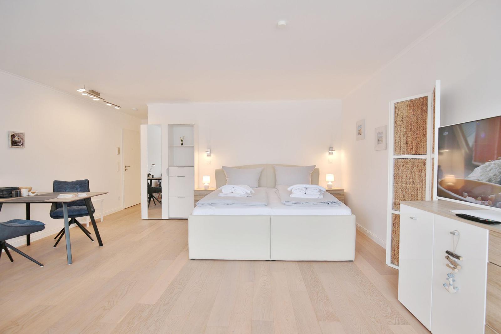 Schlafzimmer mit Bett, Schreibtisch und Fernseher.