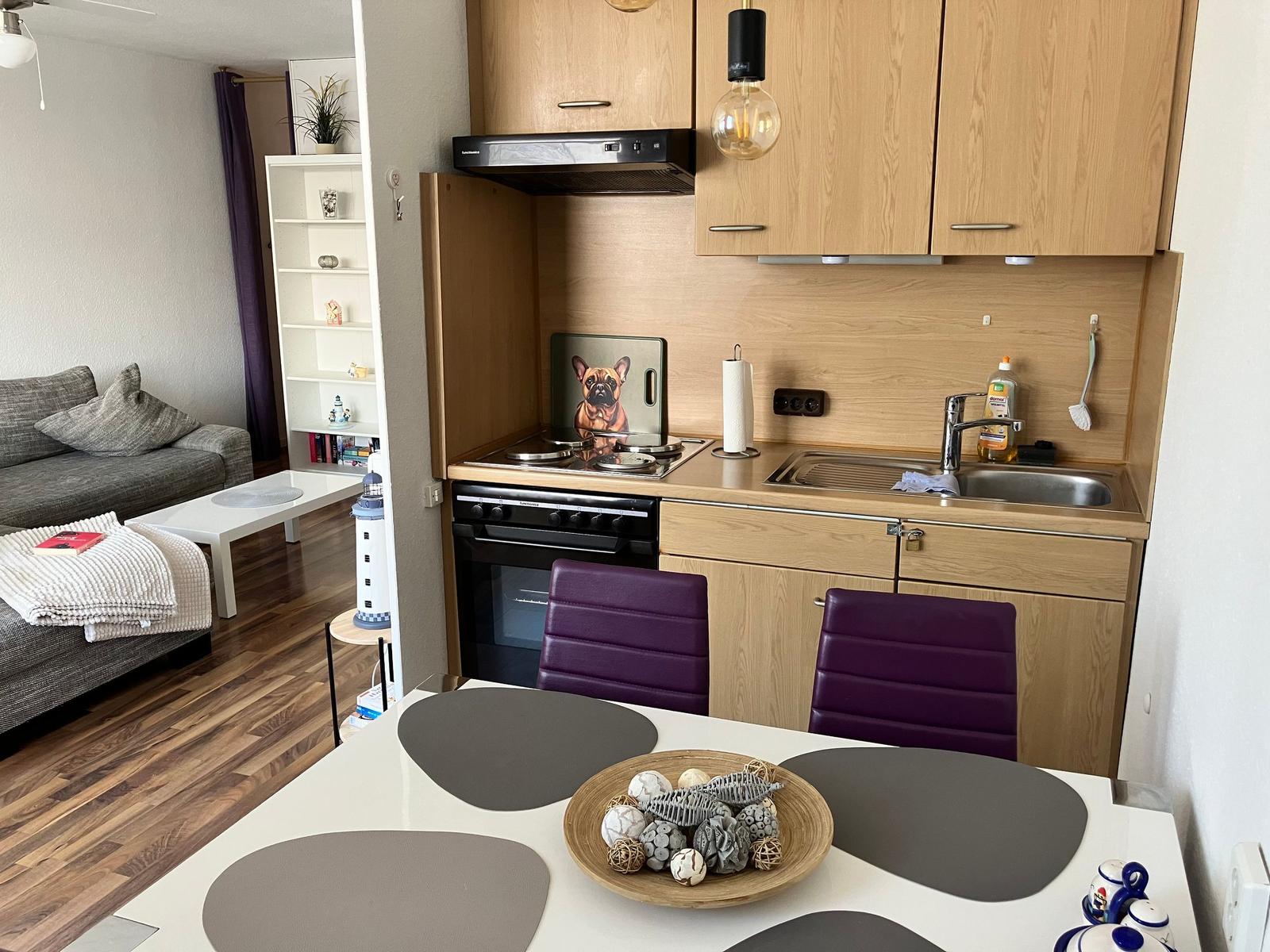 Küche mit Essbereich und Wohnzimmer im Hintergrund.