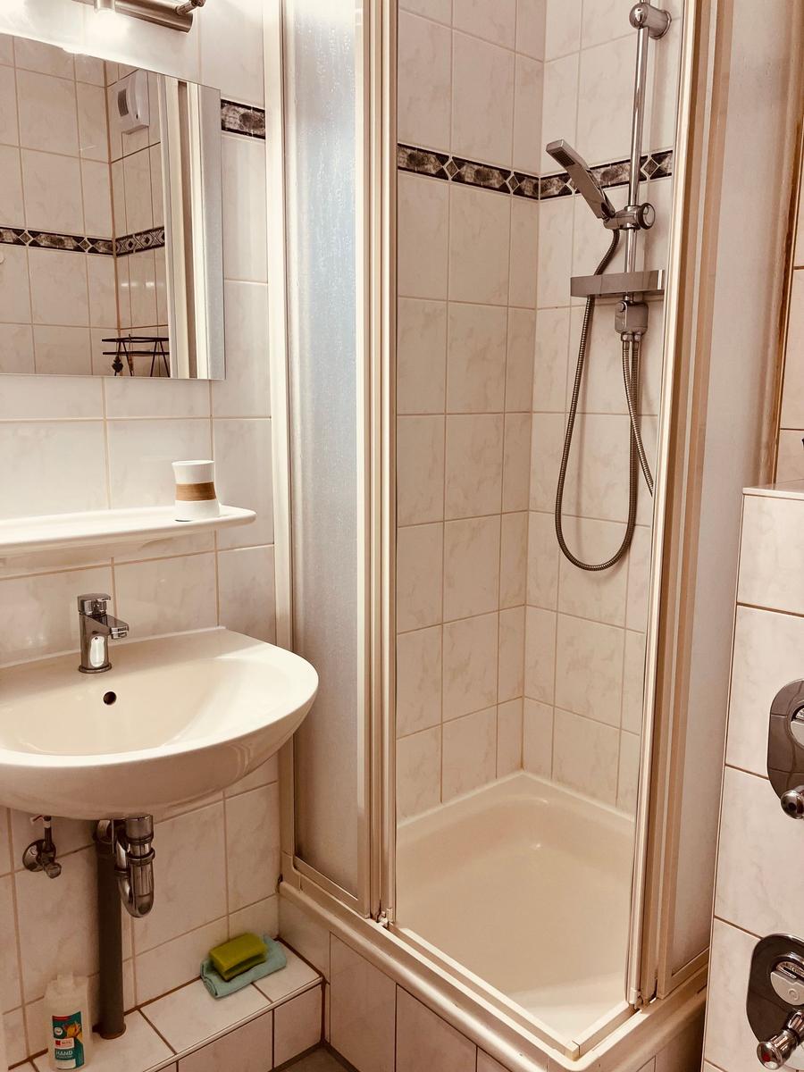 Badezimmer mit Dusche, Waschbecken und Spiegel.