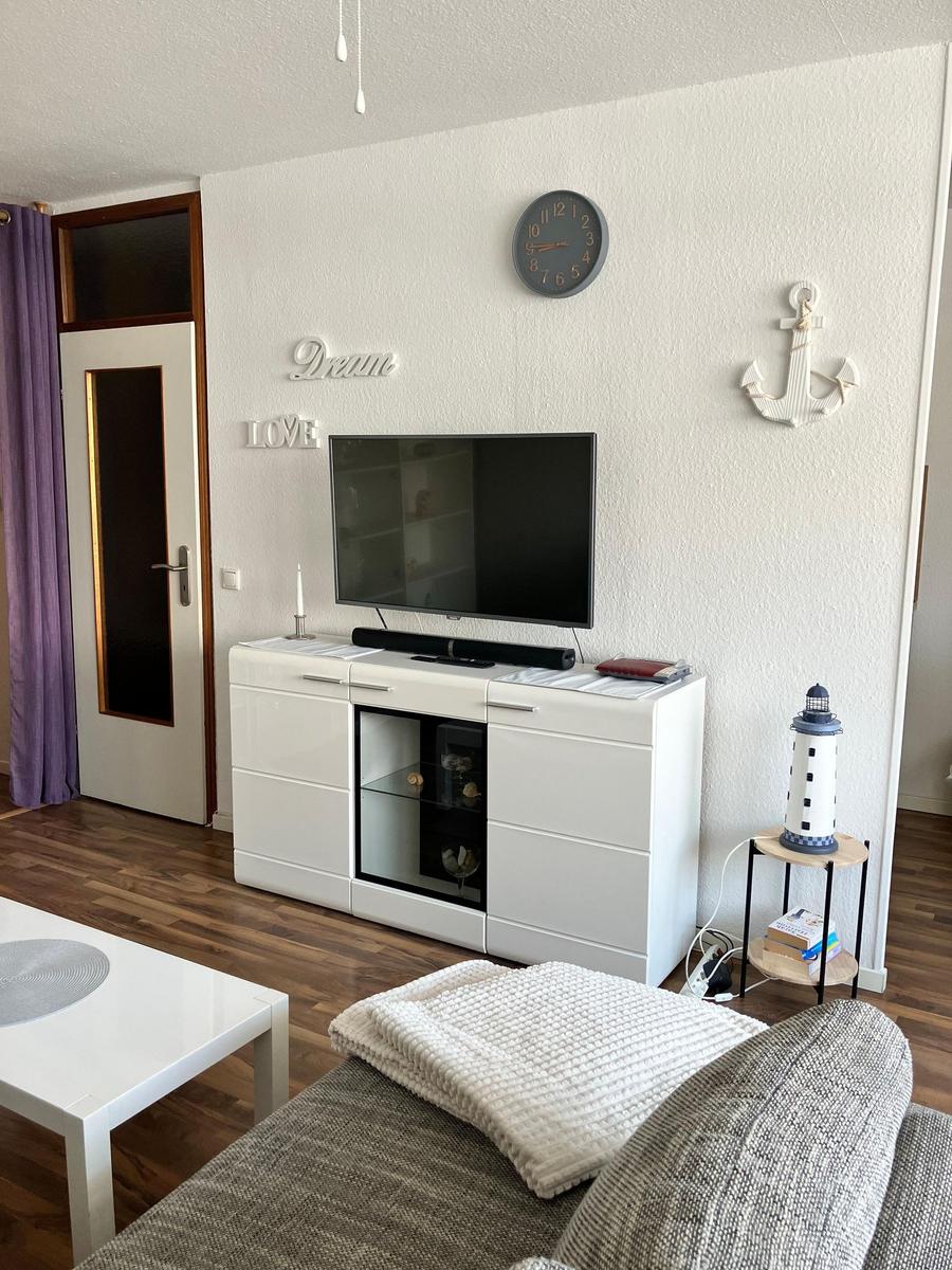 Wohnzimmer mit Fernseher, Sofa und Dekoration an der Wand.