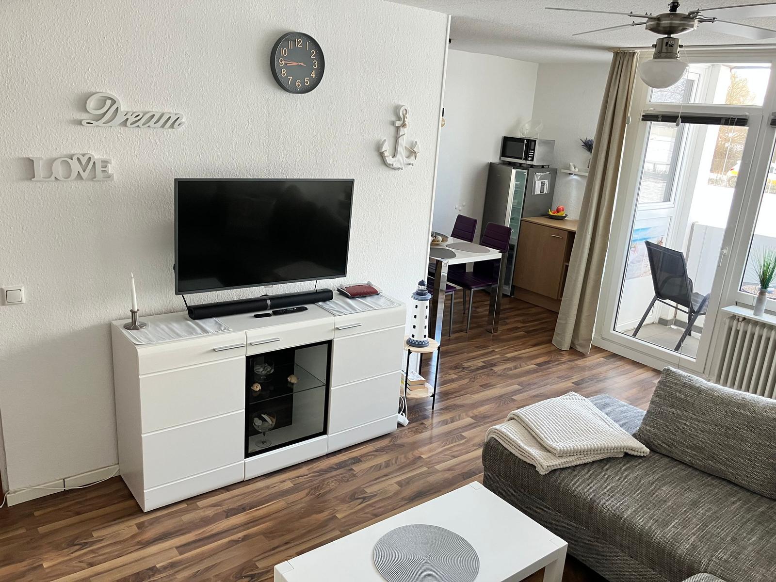 Wohnzimmer mit TV, Sofa und Blick auf Balkon