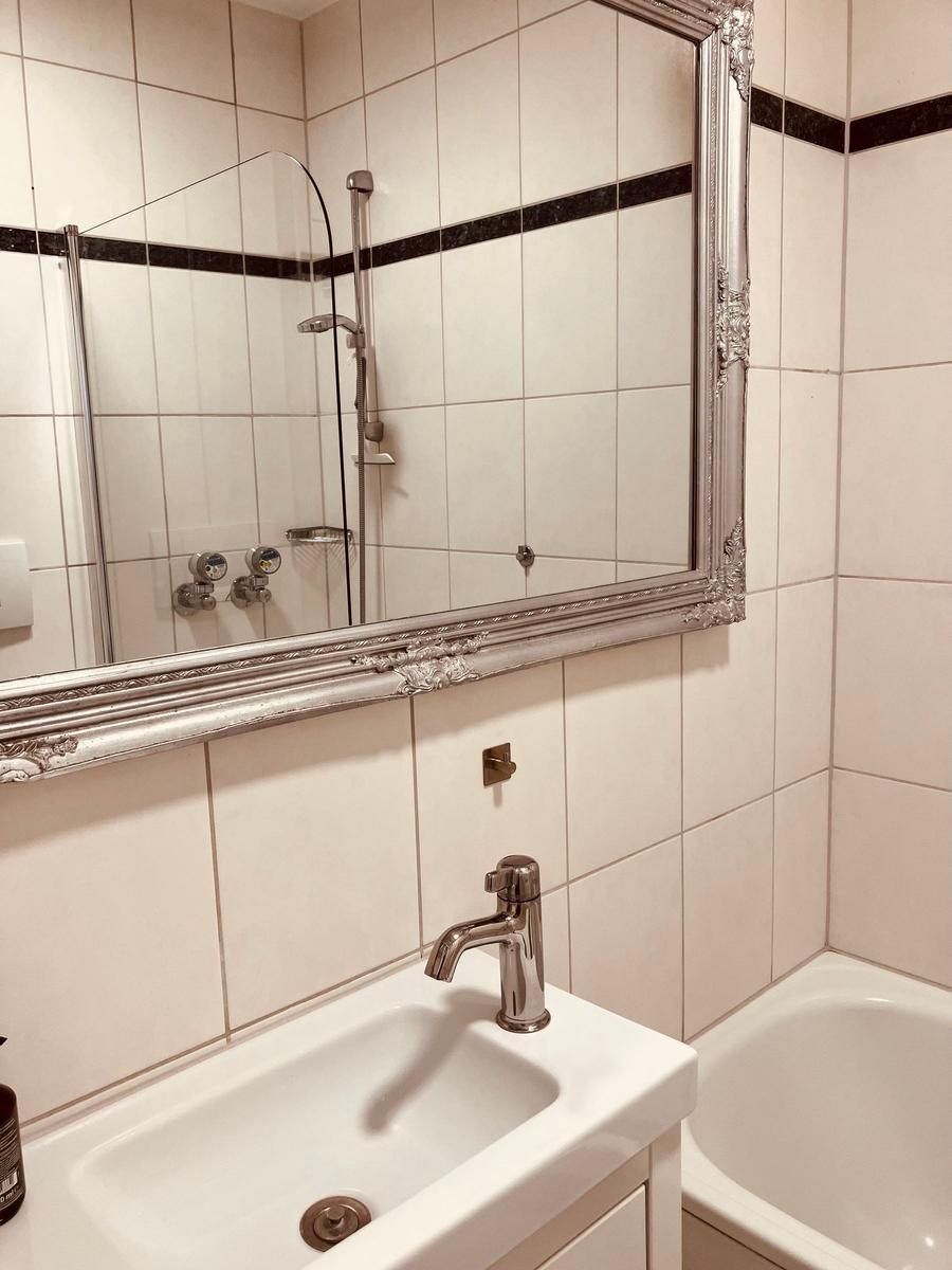 Badezimmer mit Waschbecken, Spiegel und Badewanne