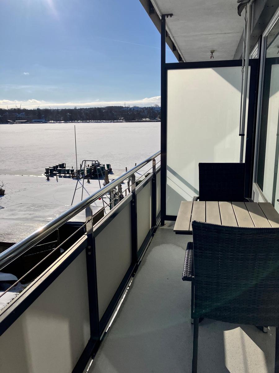 Balkon mit Tisch und Stühlen, Blick auf gefrorenen See.