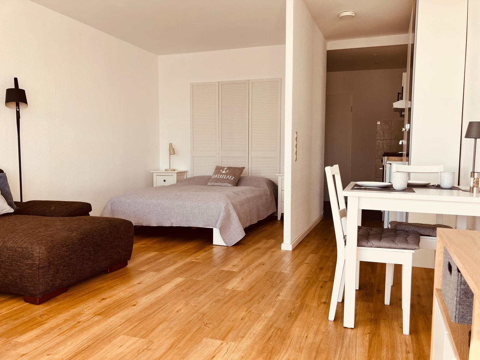 Schlafzimmer mit Bett, Kleiderschrank und Sitzgelegenheit. Nebenraum mit Esstisch und Stühlen.