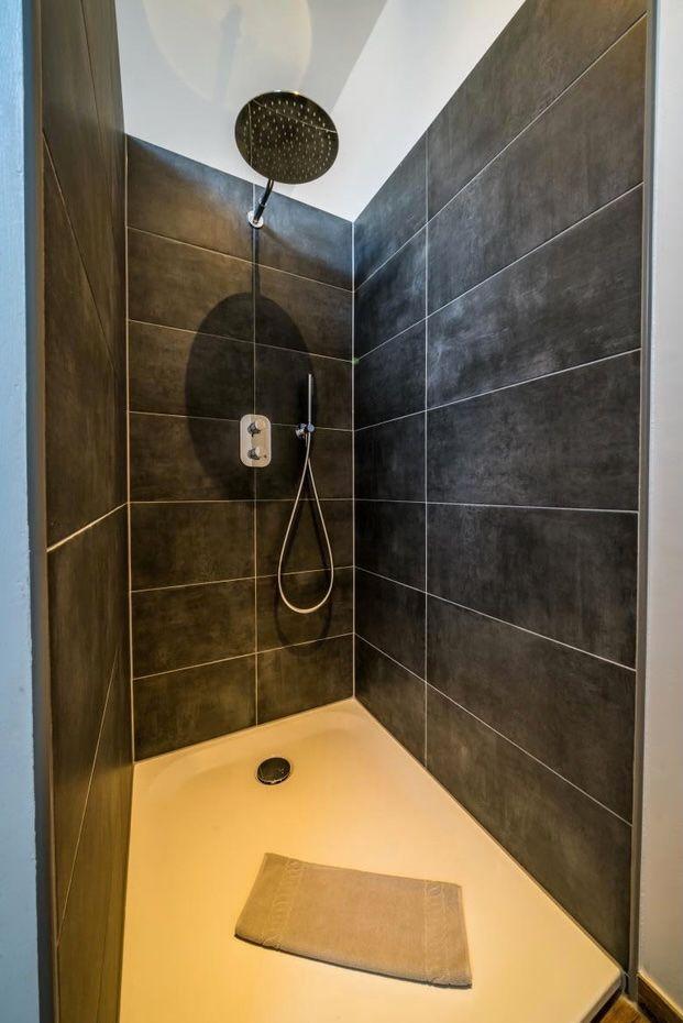 Duschkabine mit dunklen Fliesen und runder Duschkopf