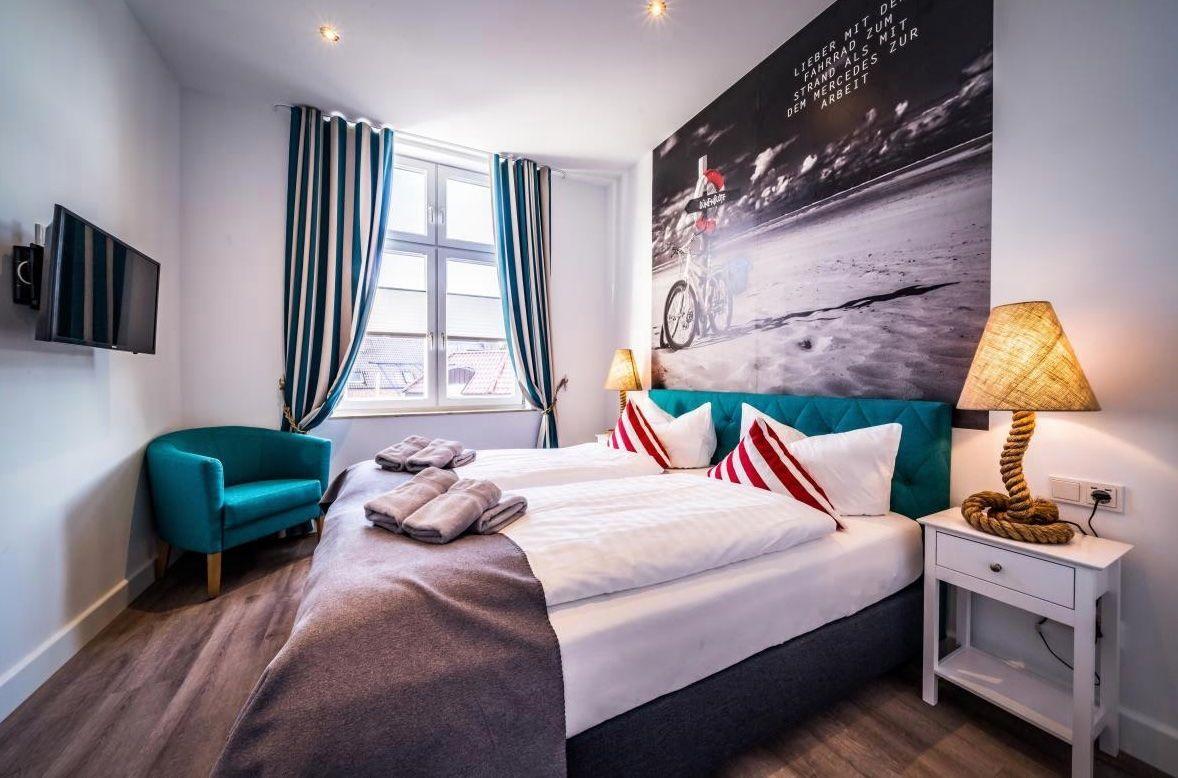 Schlafzimmer mit Doppelbett, Fenster, TV und Wandbild.