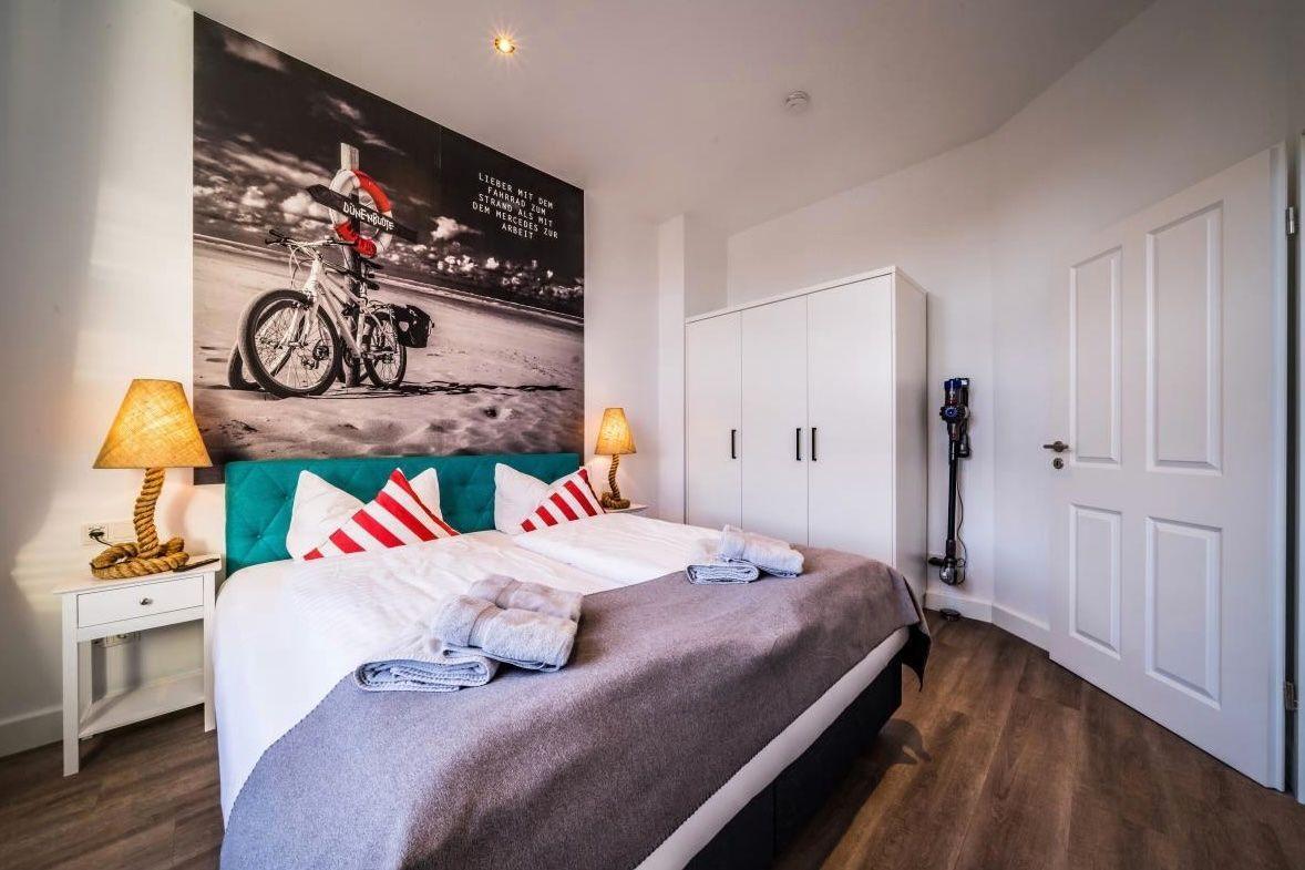 Schlafzimmer mit Bett, Kleiderschrank und Wandbild mit Fahrrad