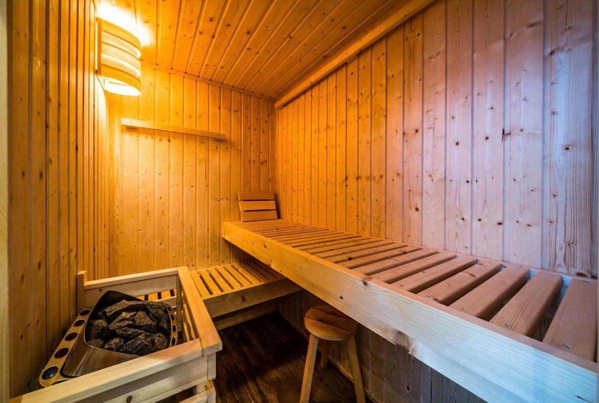 Holzsauna mit Sitzbänken und Heizung. Warmes Licht und hölzernes Ambiente.