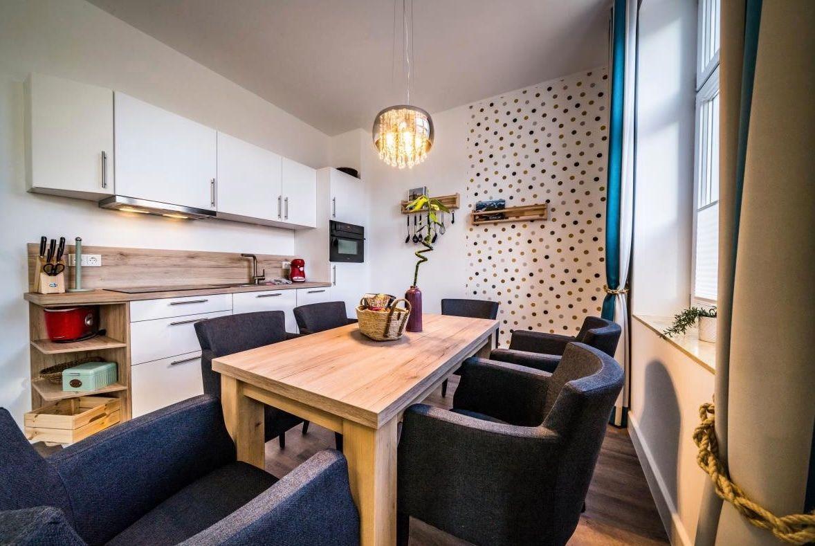 Küche und Essbereich mit Holztisch, Stühlen und Wand mit Punkten.