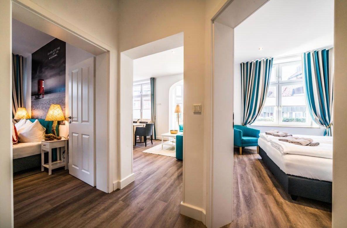 Durchgang zu drei Räumen mit Bett, Sofa und Fenster