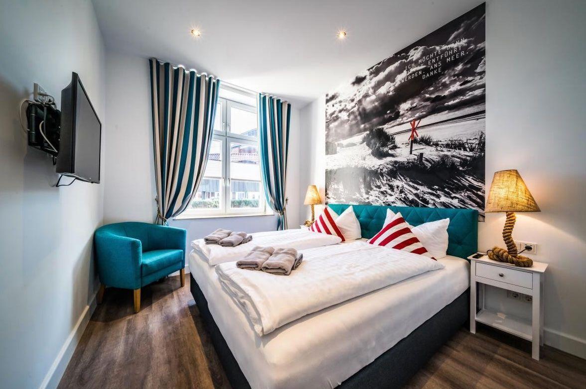 Schlafzimmer mit Doppelbett, Fenster, TV und Wandbild.