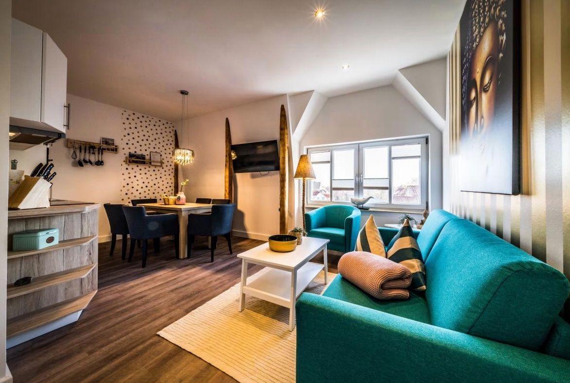 Wohn- und Essbereich mit Sofa, Tisch und Küchenzeile.