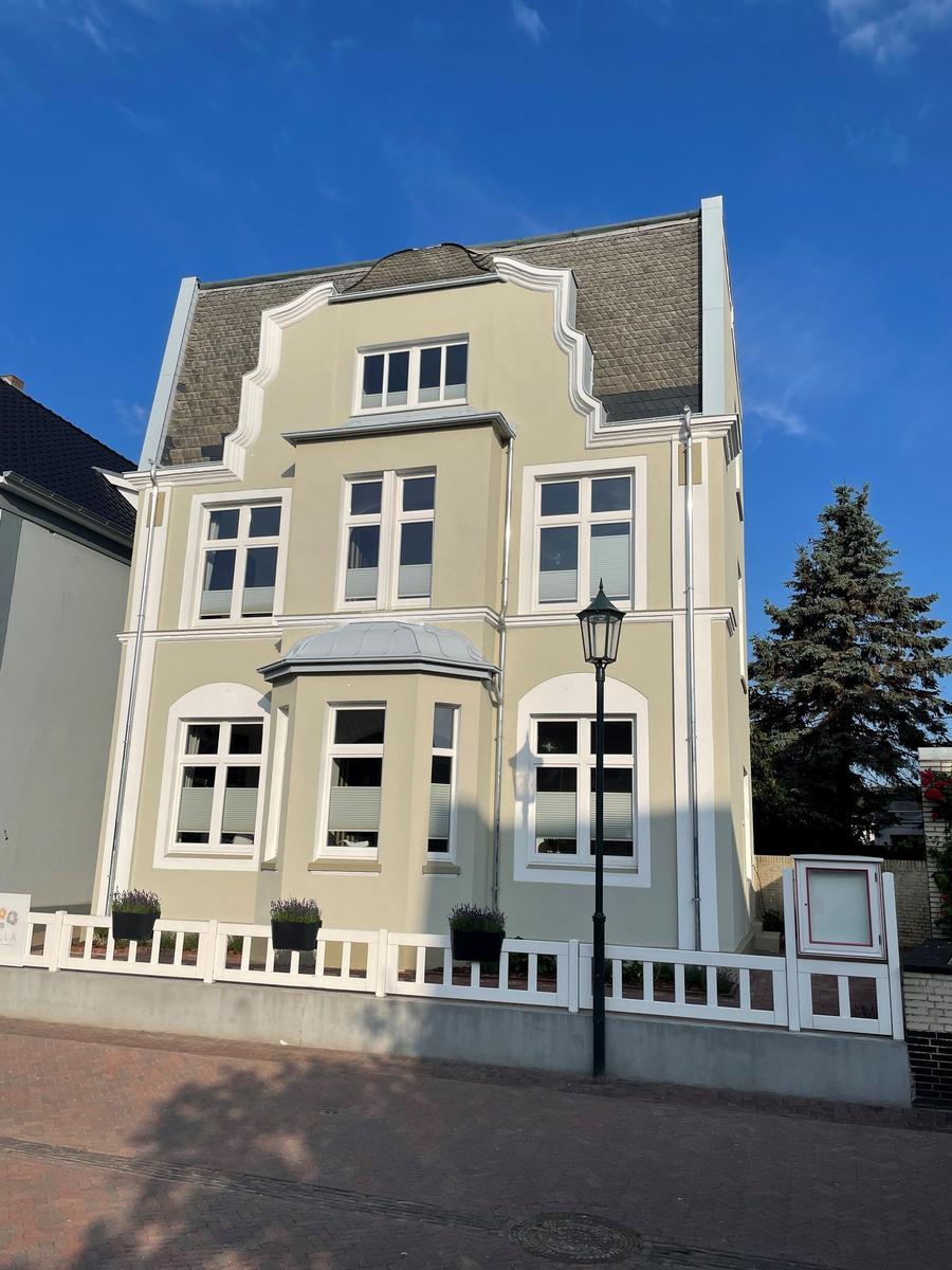 Ein dreigeschossiges Haus mit hellen Fenstern und weißer Fassadendekoration.