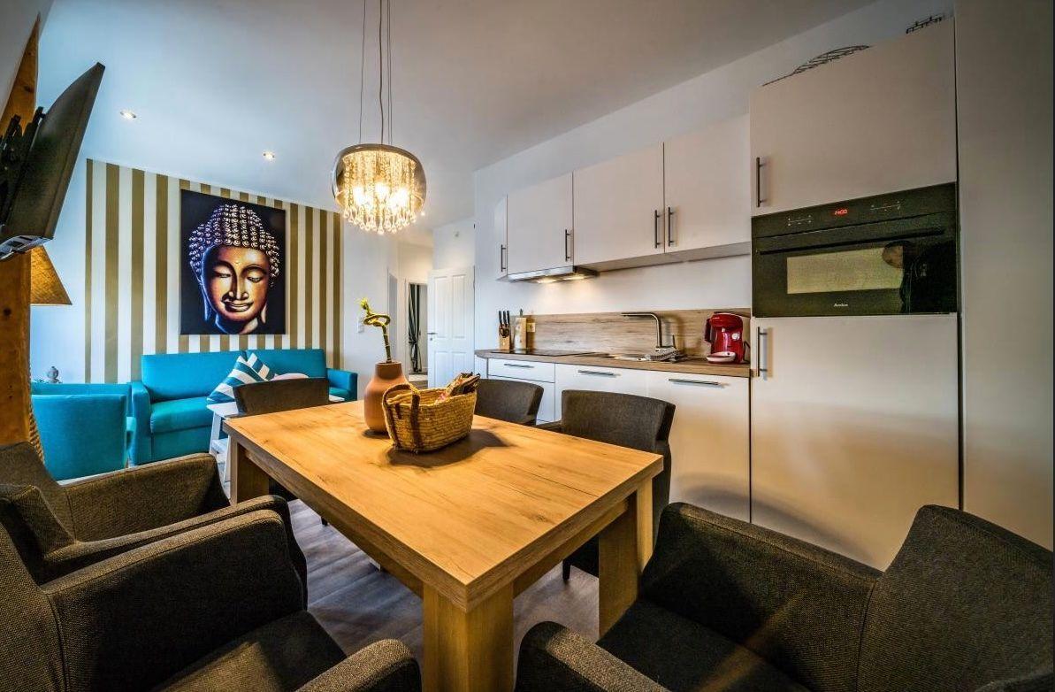 Essbereich mit Holztisch, Küchenzeile und Buddha-Bild an der Wand.