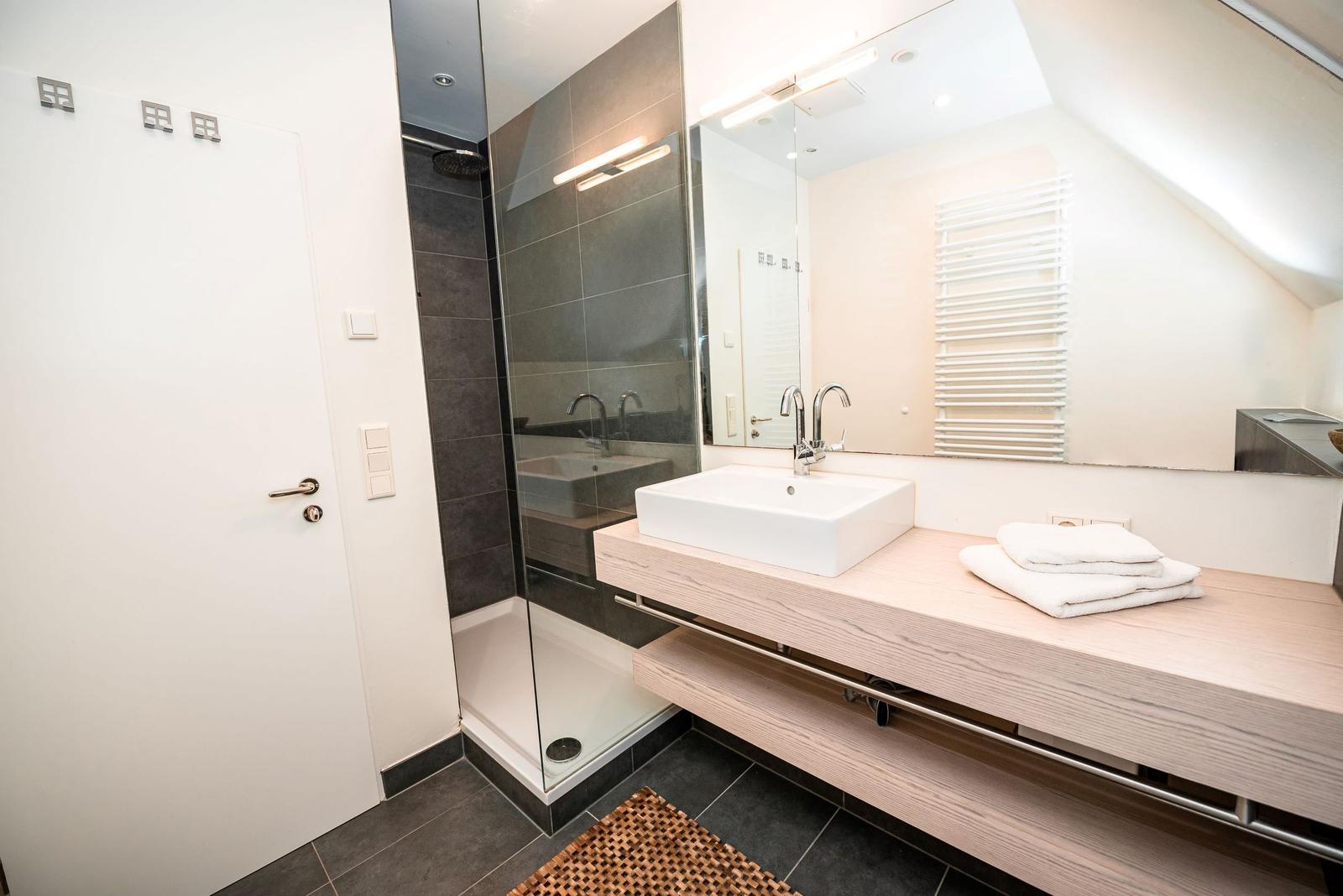 Badezimmer mit Dusche, Waschbecken und Handtuch