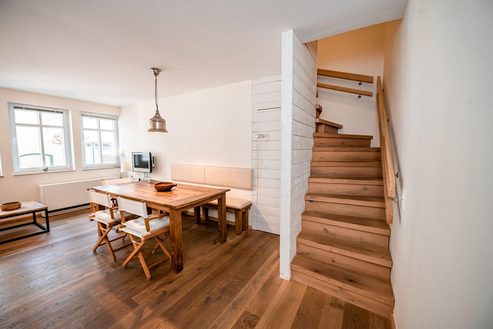 Essbereich mit Holztisch, Stühlen und Treppe zur oberen Etage.