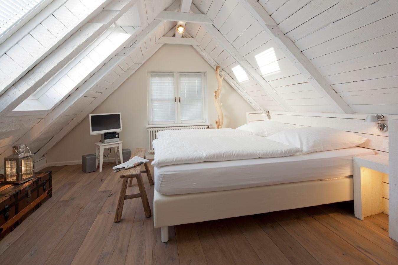 Schlafzimmer mit Dachschrägen, Bett, Fenster und Holzboden.