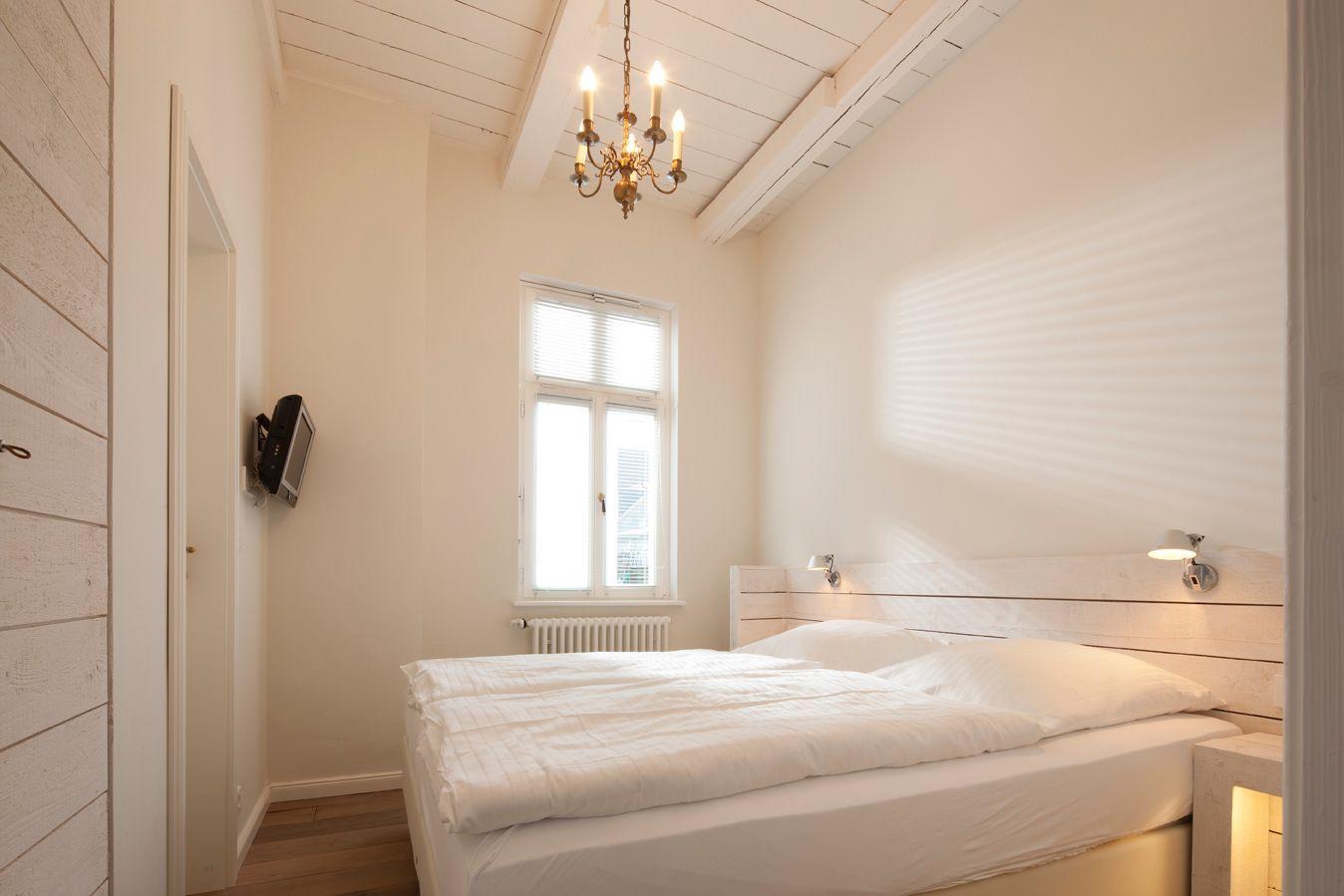 Schlafzimmer mit Bett, Fenster und Kronleuchter.