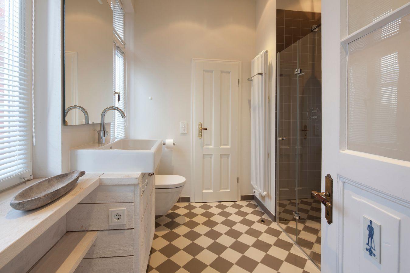 Badezimmer mit Dusche, Waschbecken und Toilette auf schwarz-weißem Fliesenboden.
