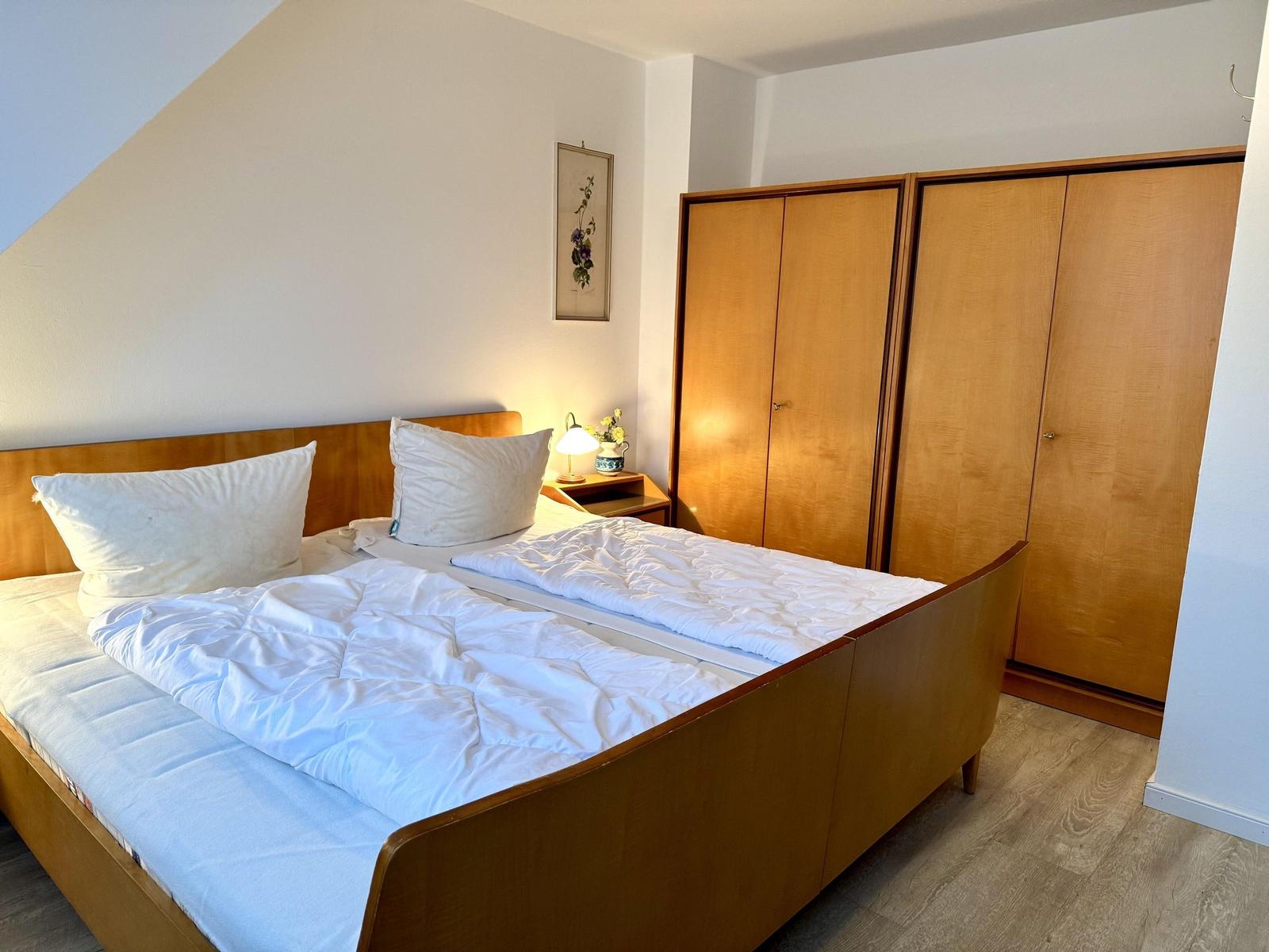 Schlafzimmer mit Bett, Kleiderschrank und Nachttisch.