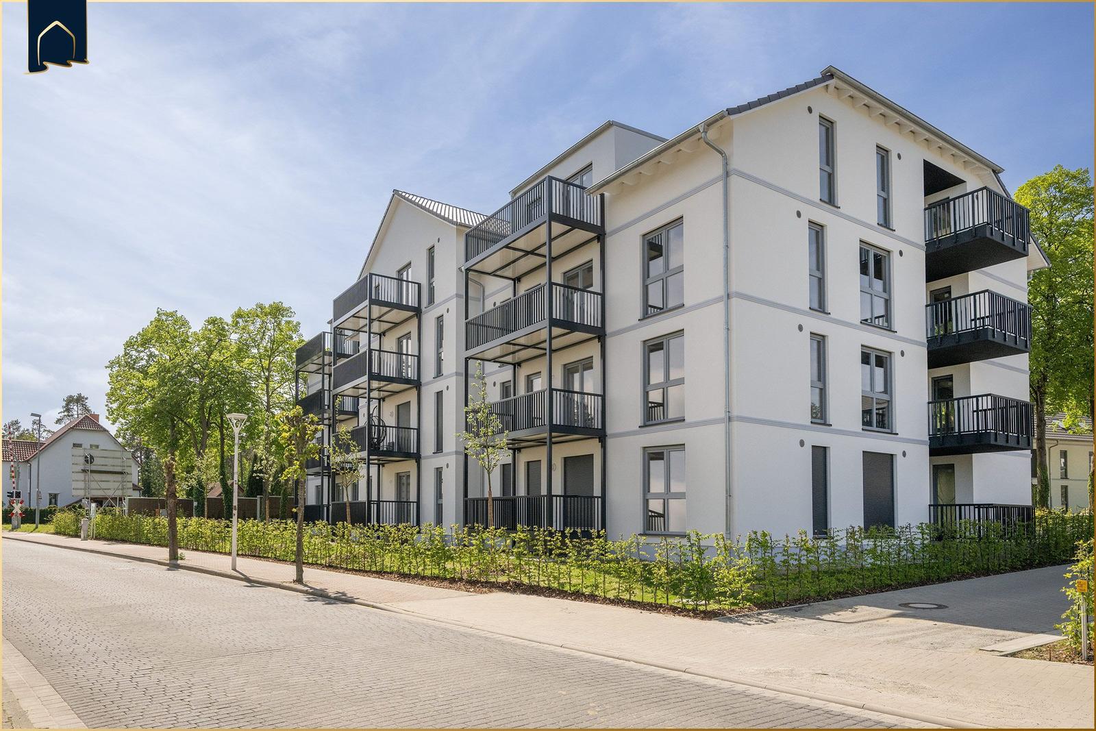 Modernes Mehrfamilienhaus mit Balkonen und grüner Umgebung.