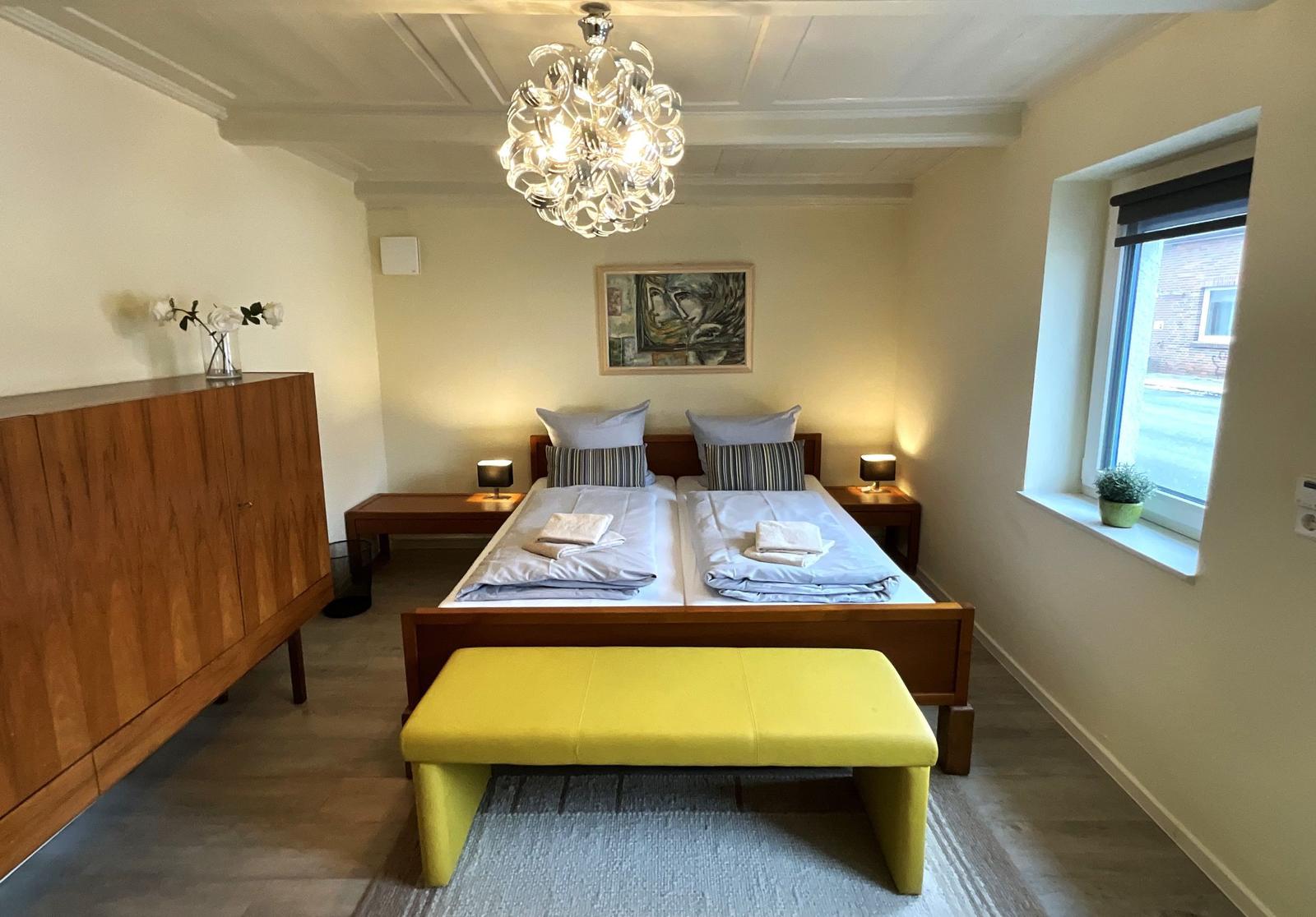 Schlafzimmer mit Doppelbett, Holzmöbel und gelbem Sitzbank.