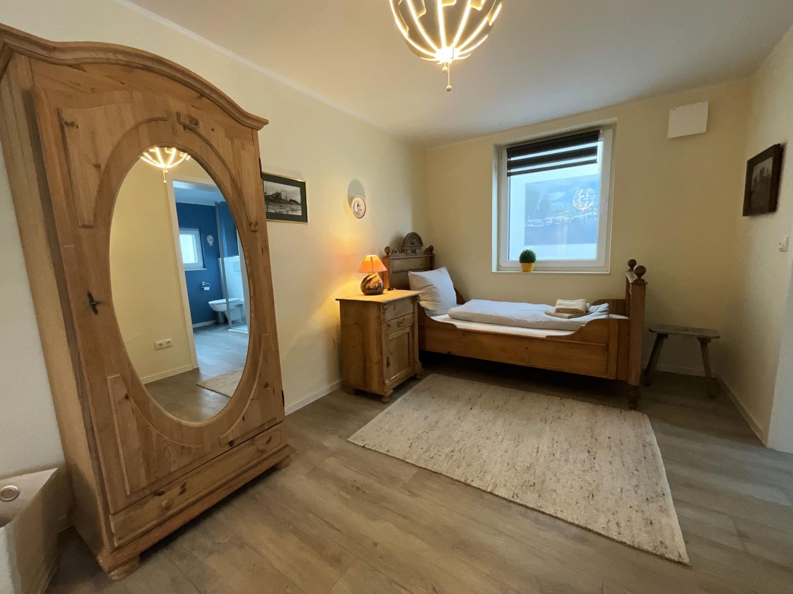 Schlafzimmer mit Holzbett, Kleiderschrank und Fenster