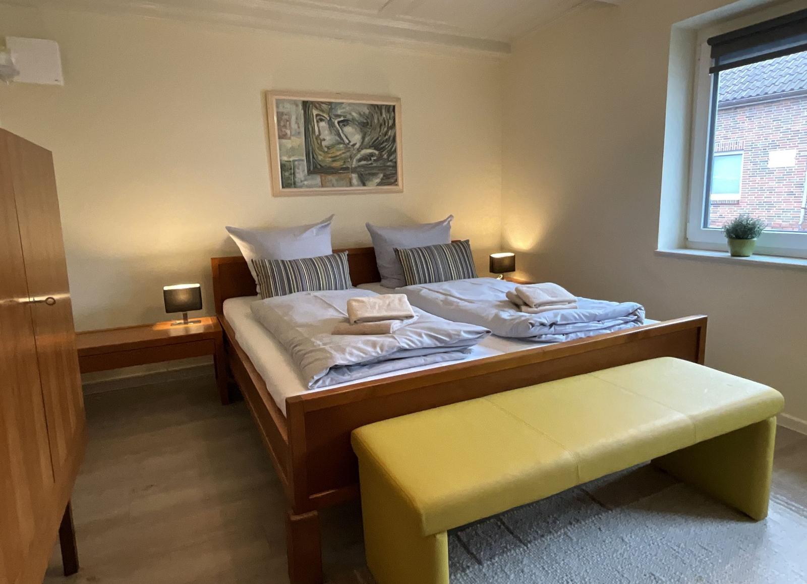 Schlafzimmer mit Doppelbett, Nachttischen und Fenster.