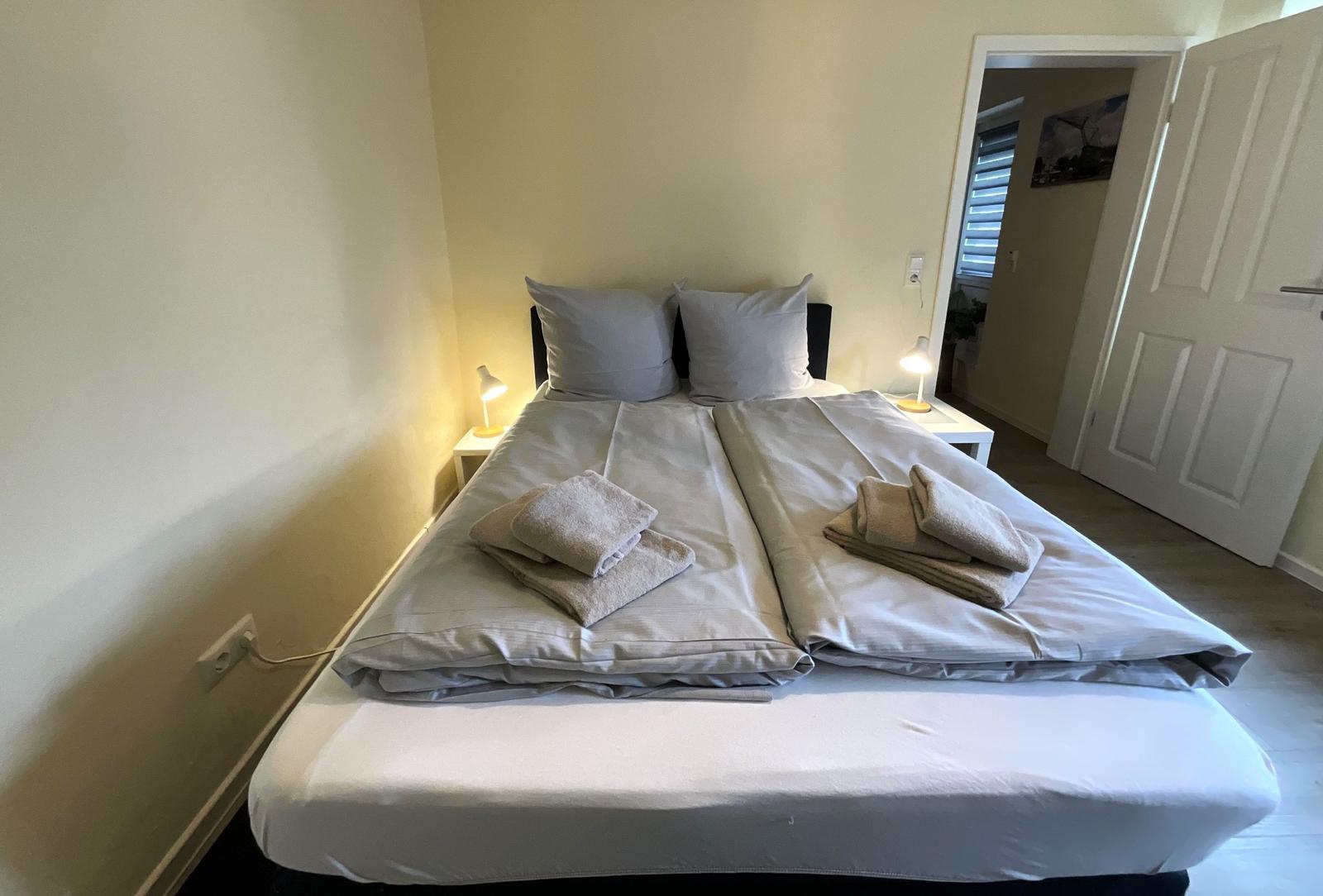 Schlafzimmer mit Doppelbett, zwei Nachttischen und Lampen.