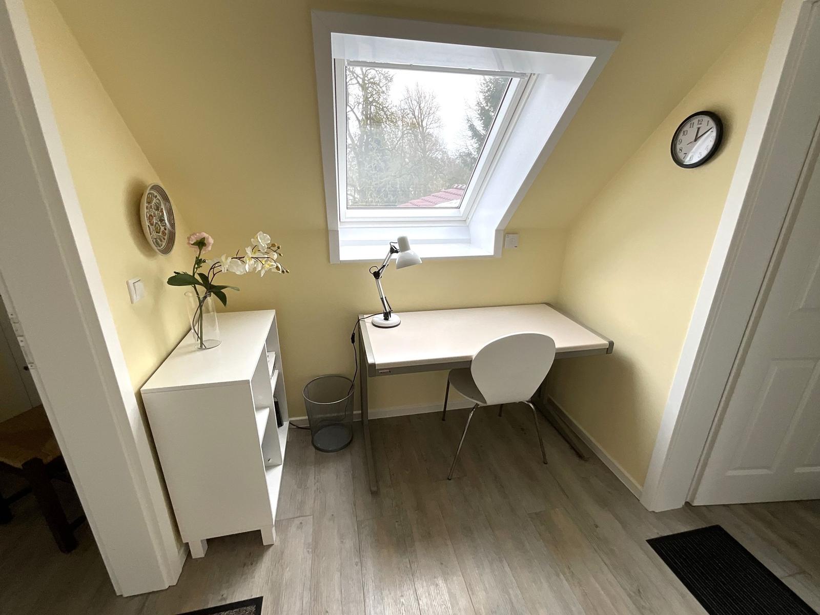 Arbeitszimmer mit Schreibtisch, Stuhl und Dachfenster.