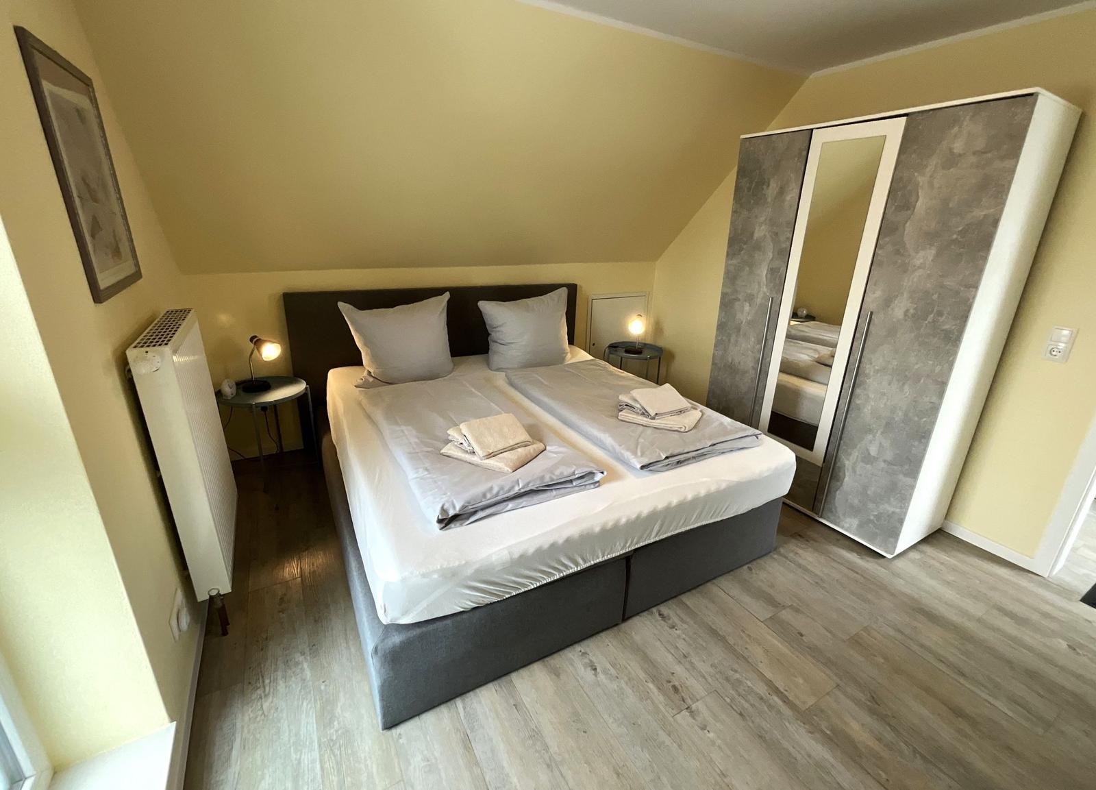 Schlafzimmer mit Doppelbett, Kleiderschrank und Nachttischen.