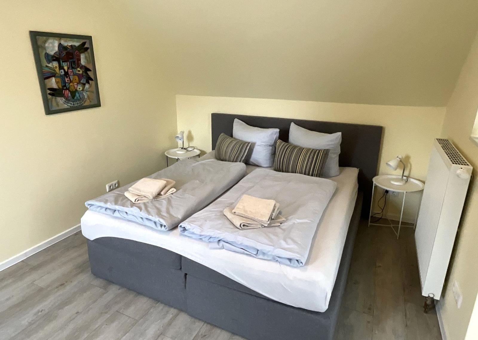 Schlafzimmer mit Doppelbett, zwei Nachttischen und Wandbild.