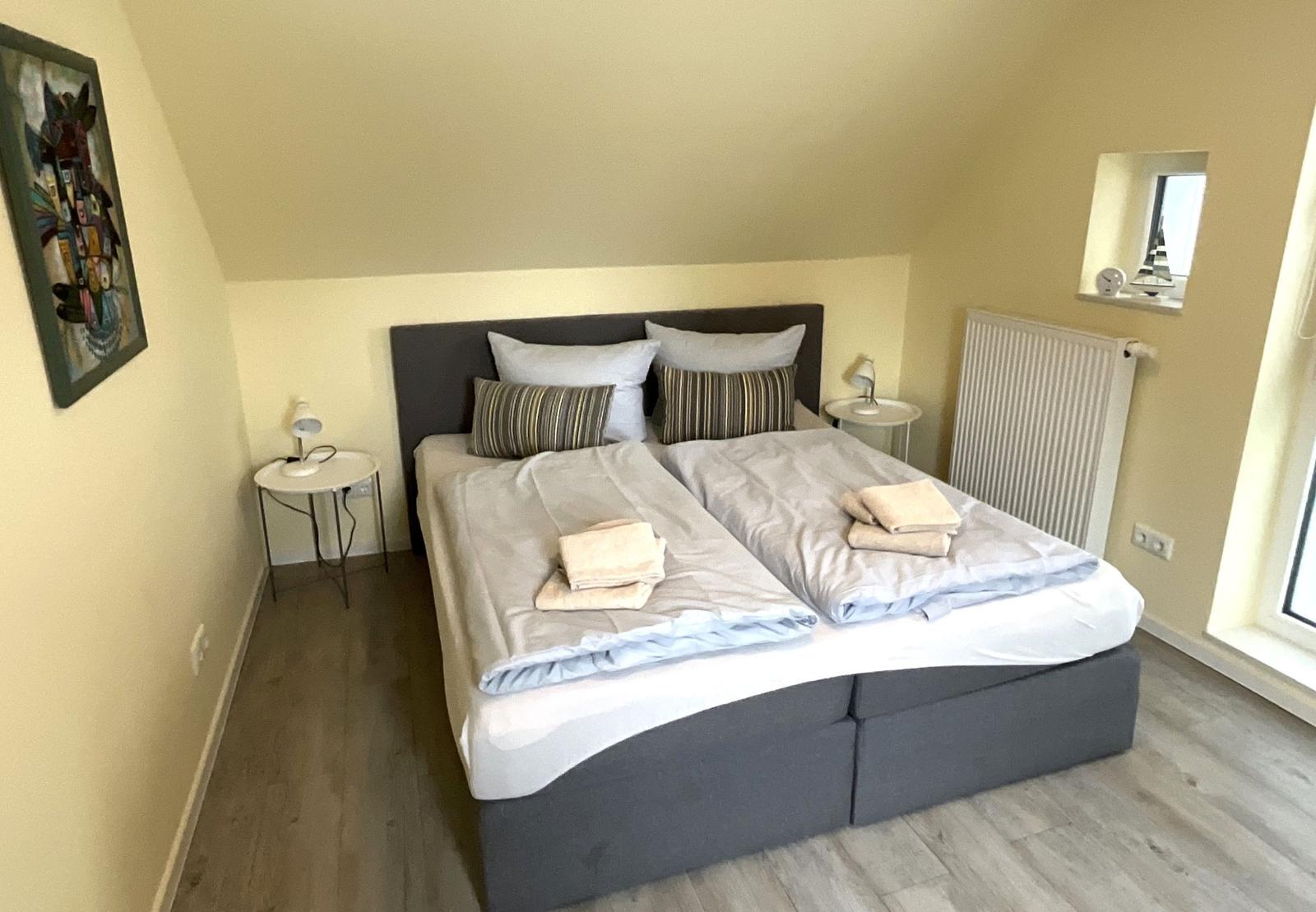 Schlafzimmer mit Doppelbett, zwei Nachttischen und Fenster.