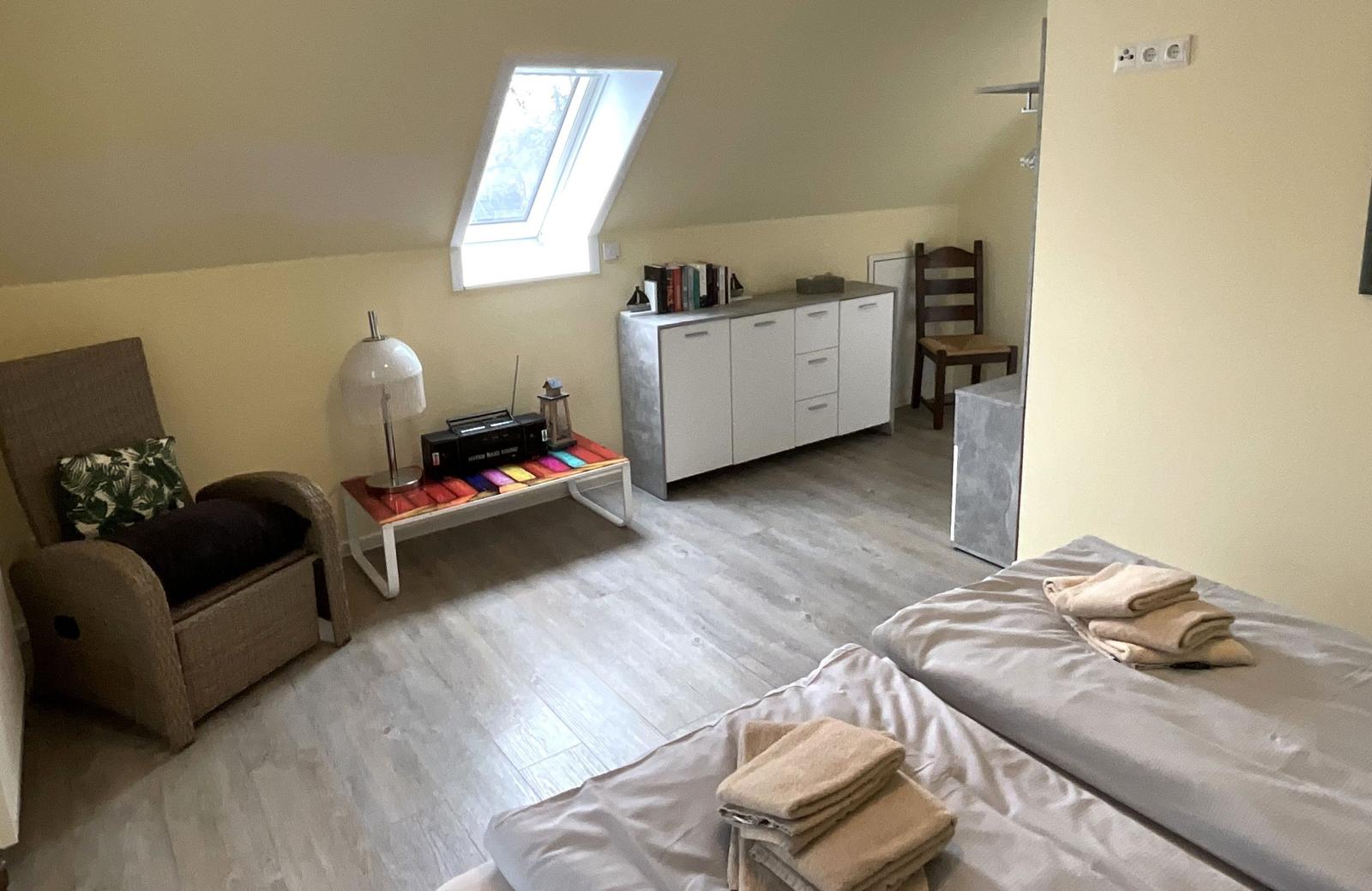 Zimmer mit Dachschrägen, zwei Betten, Schrank und Sitzgelegenheit.