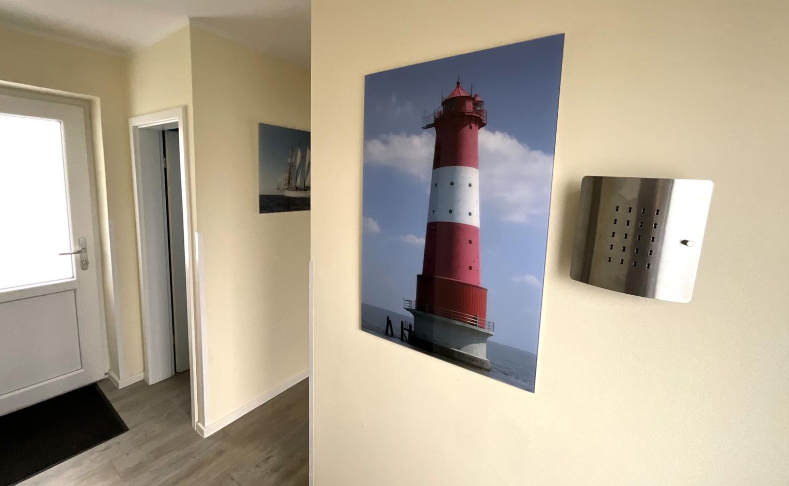 Hausgang mit rotem Leuchtturm-Bild und moderner Wandplatte.